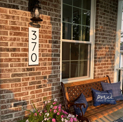 Vertical address sign with black numbers on a white background for improving outdoor garden